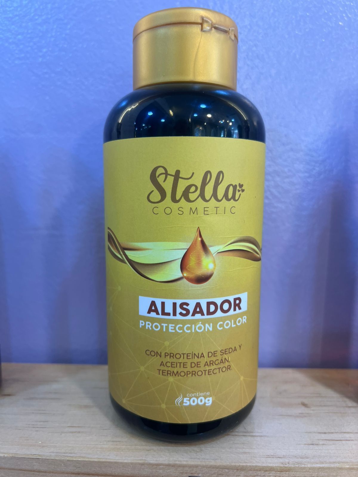 Botella de plancha de pelo Stella Cosmetic con etiqueta dorada y amarilla.