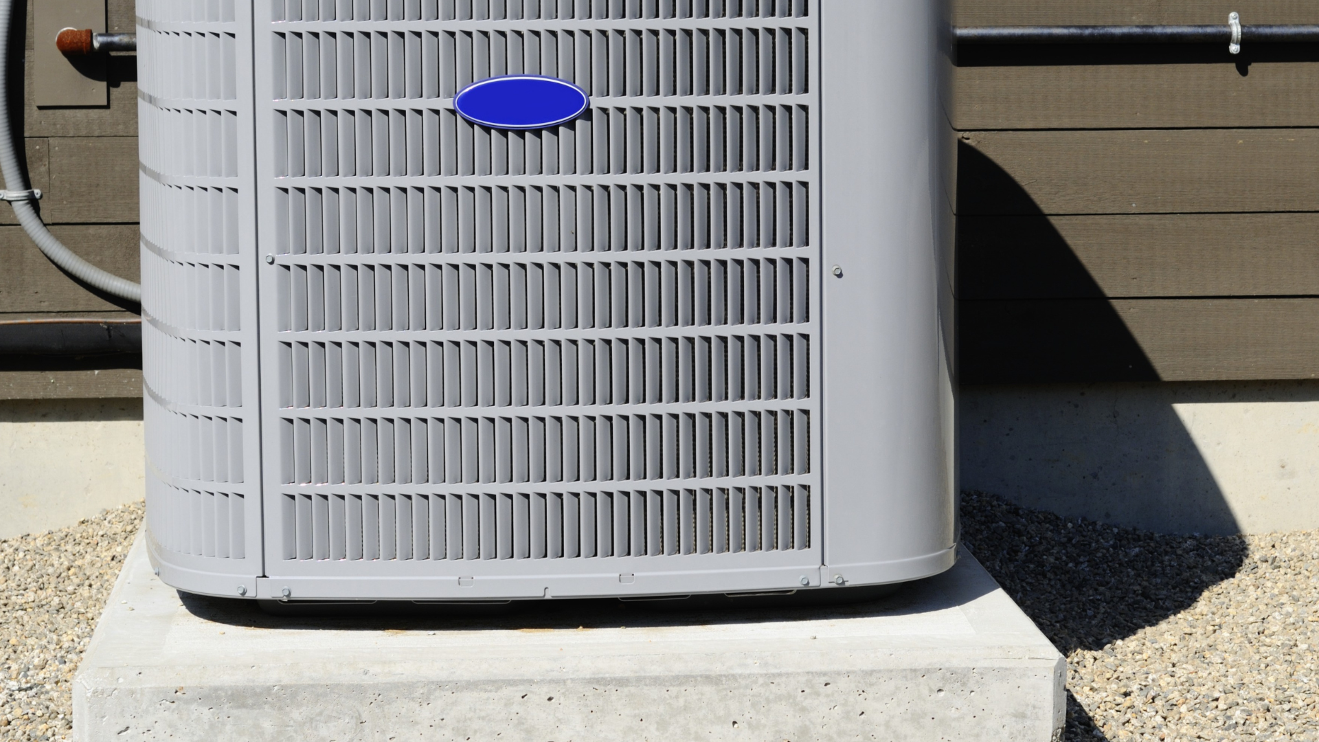 Outdoor central air conditioner unit on a concrete pad beside a house.