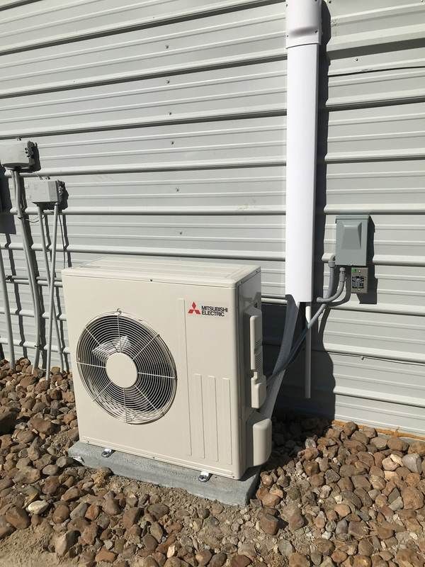 Mitsubishi heat pump unit outside building with gravel.