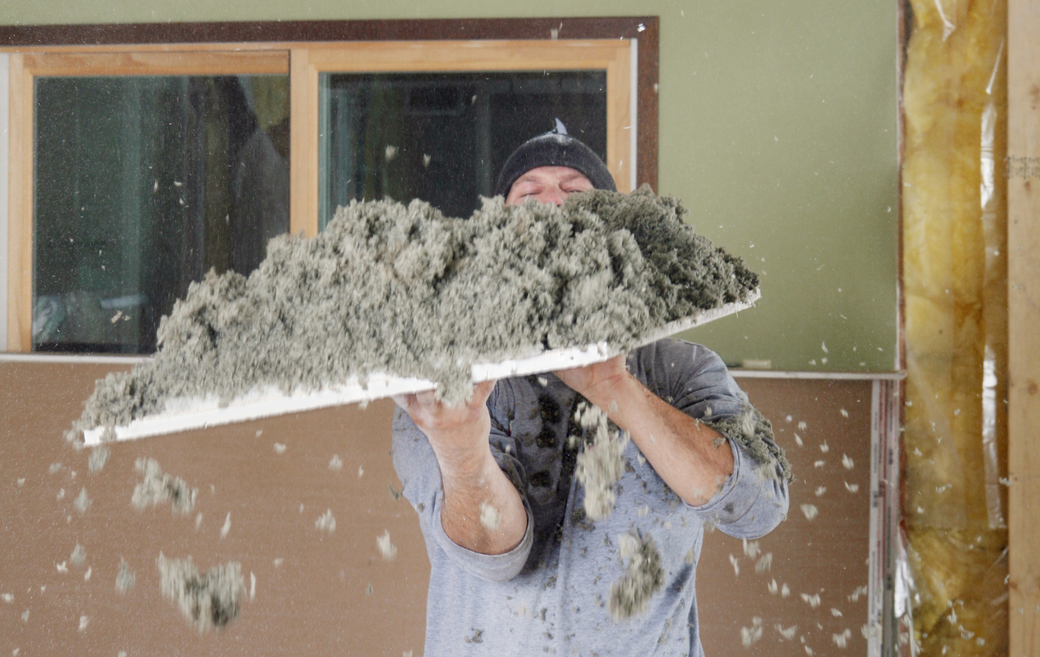 A man is holding a piece of styrofoam in his hands that has old insulation ontop of it