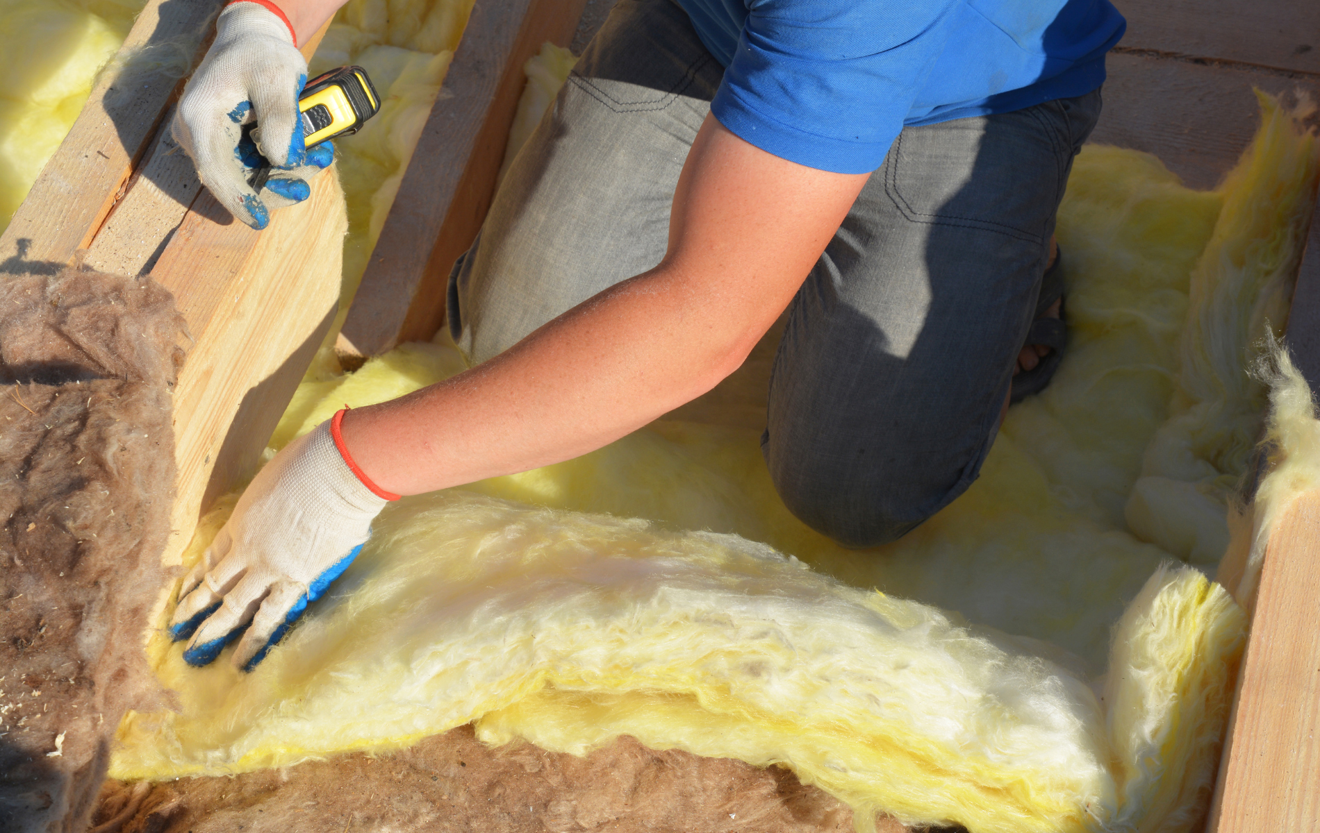 A person is measuring a piece of insulation with a tape measure.
