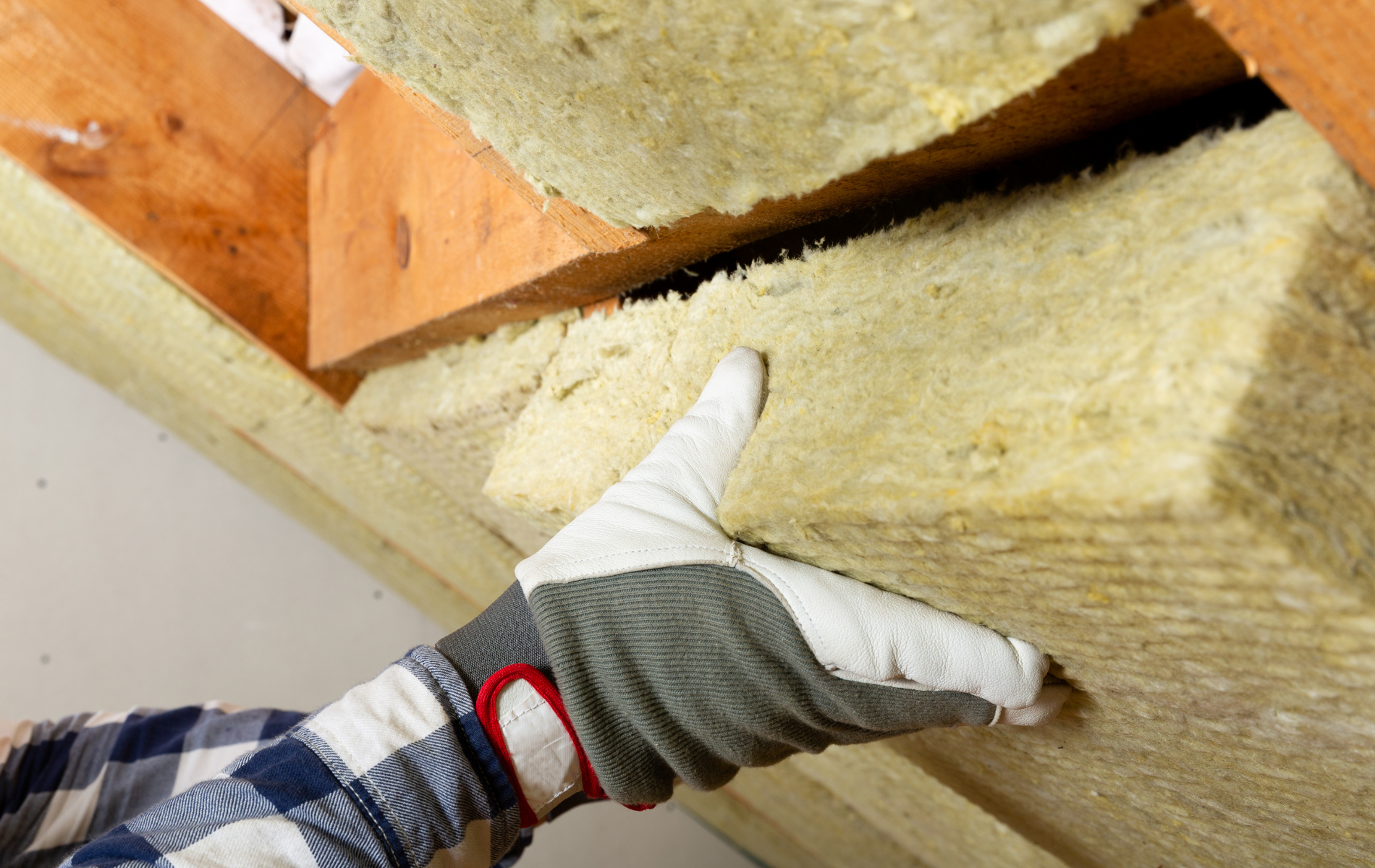 A person wearing gloves is holding a piece of insulation.