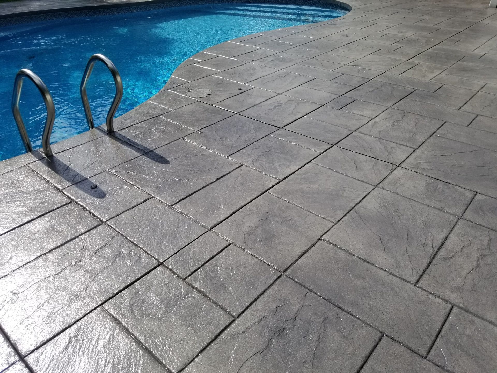 A swimming pool with a stamped concrete deck and stairs