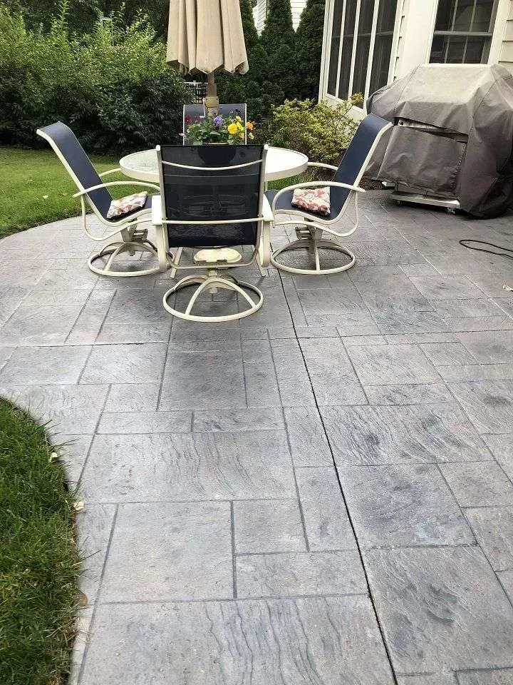 A stamped concrete patio with a table and chairs and an umbrella.