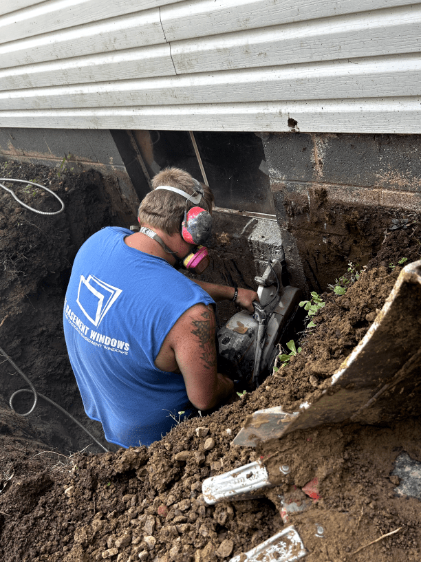 A man in a blue shirt is working in a hole in the ground.