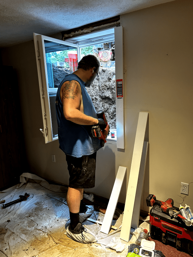 A man is working on a window in a room.