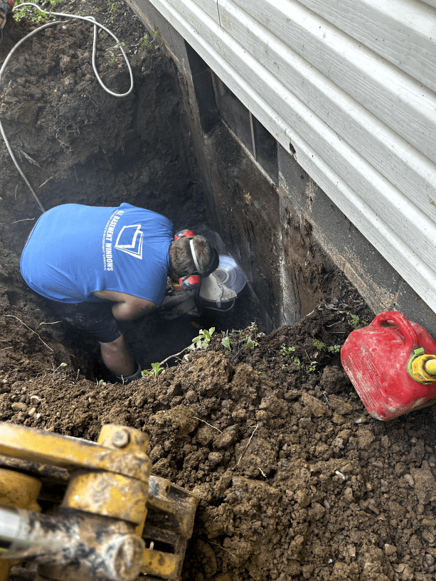 A man is digging a hole in the ground next to a gas can.