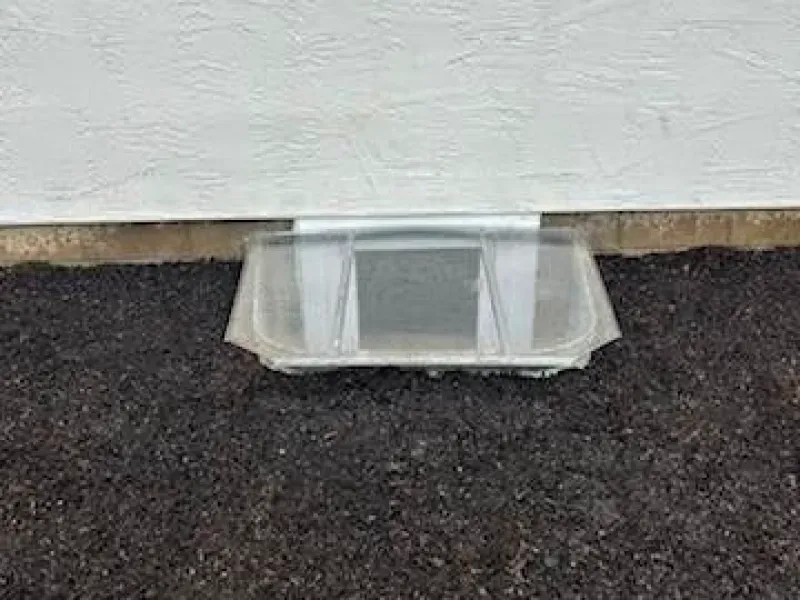 A plastic container is sitting on the ground next to a wall.