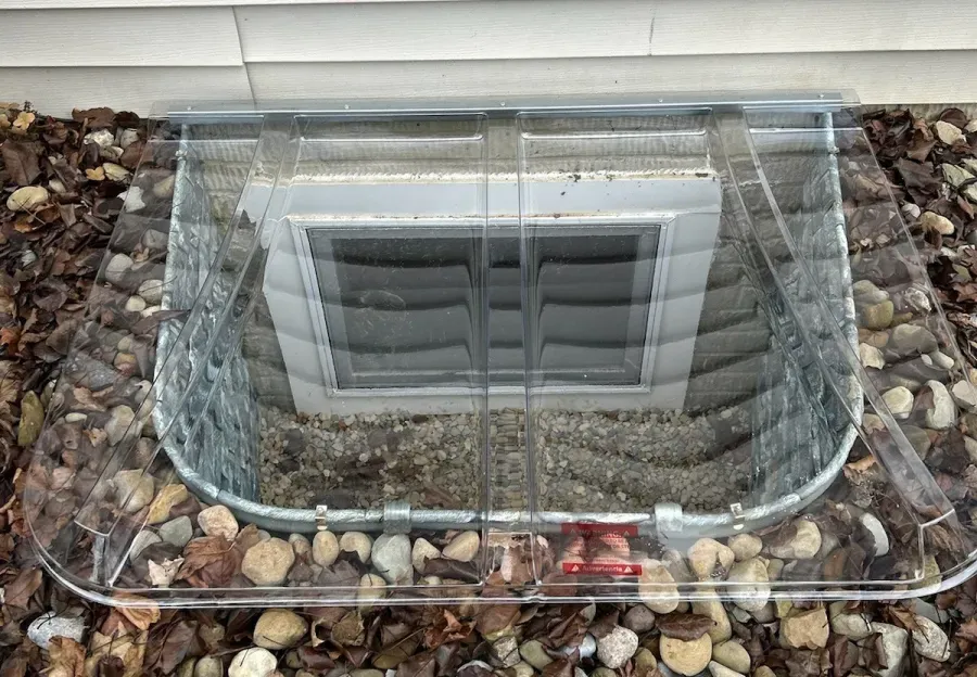 A window well with a clear cover on top of it.