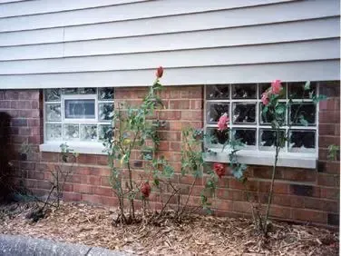 A brick wall with a window and flowers in front of it