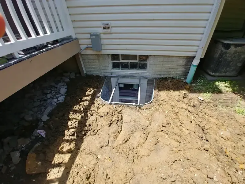 A window in the basement of a house is being installed.