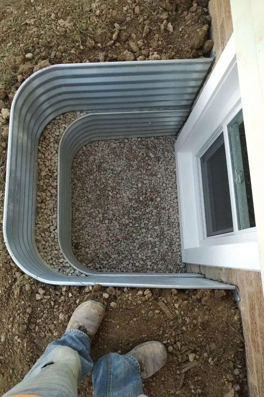 A person is standing in the dirt next to a window.