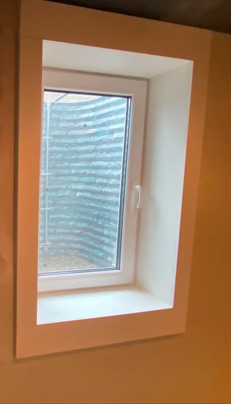 A window with blinds on it is sitting on a wall.