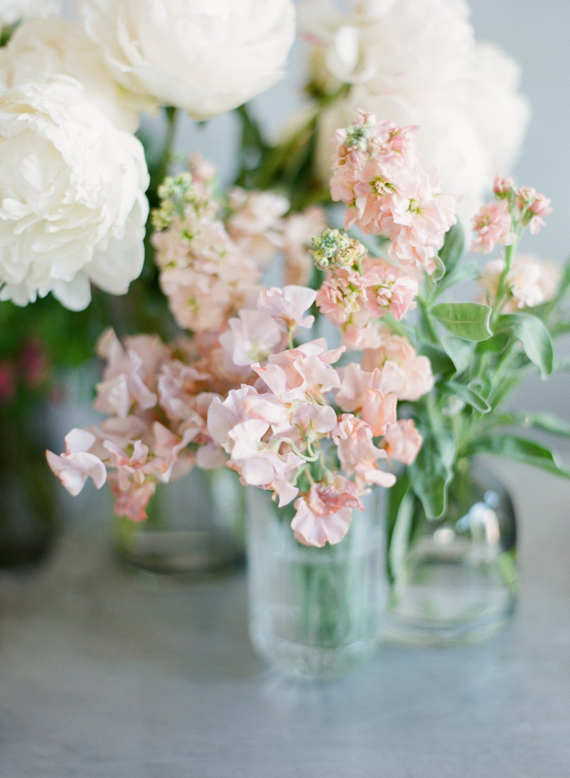Three vases filled with pink and white flowers are sitting on a table.