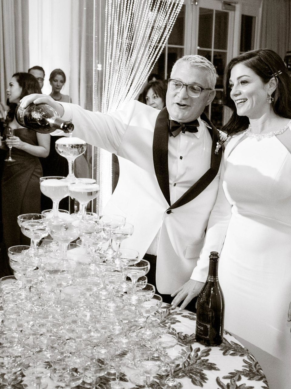 A man is pouring champagne into a pyramid of champagne glasses