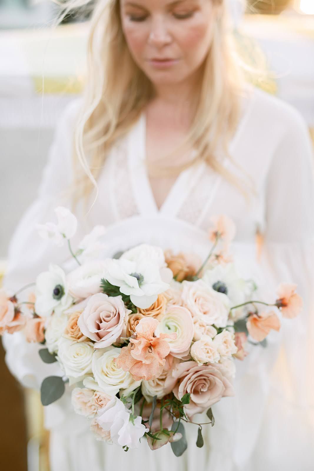 A woman in a white dress is holding a bouquet of flowers.