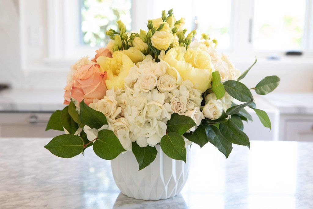 A vase filled with flowers is sitting on a counter.