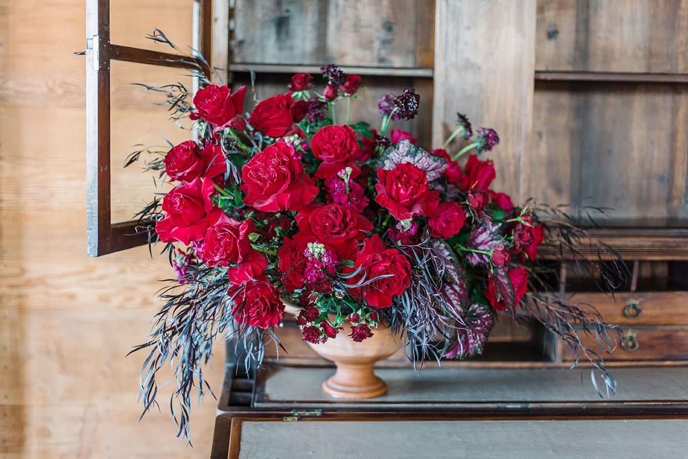 A vase filled with red flowers is sitting on a table.