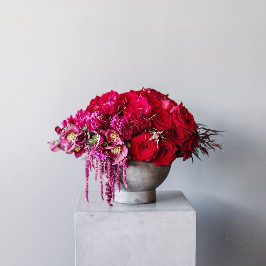 A vase filled with red roses and pink flowers