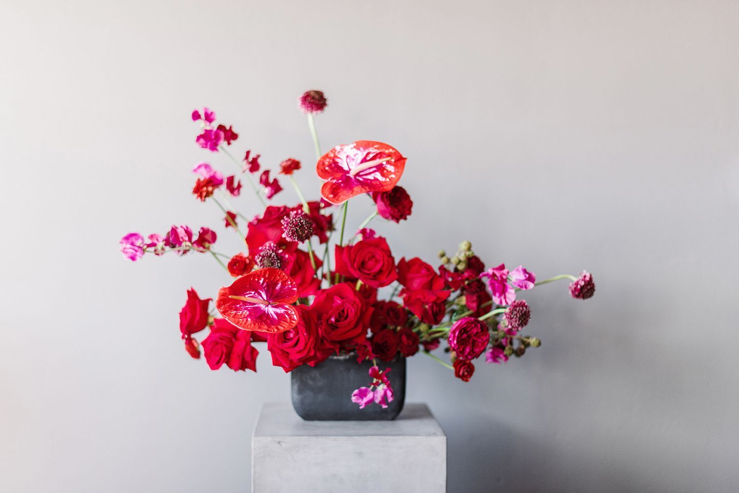 A vase filled with red flowers is sitting on top of a concrete block.