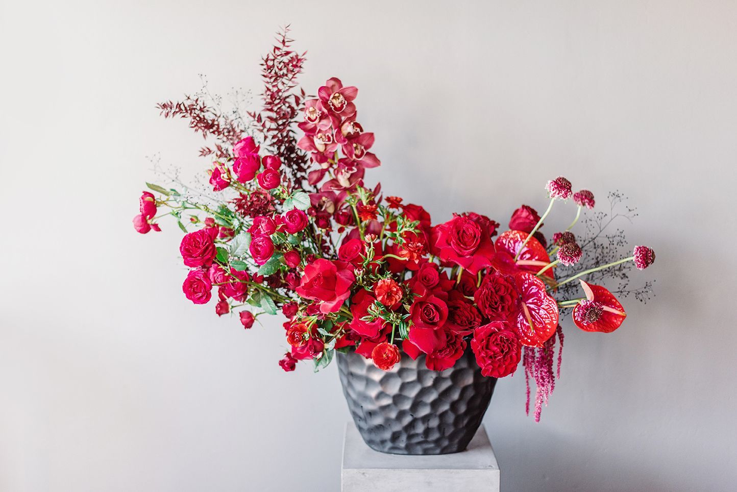 A vase filled with red flowers is sitting on a table.