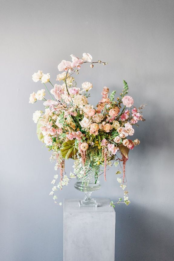 A vase filled with flowers is sitting on a pedestal.