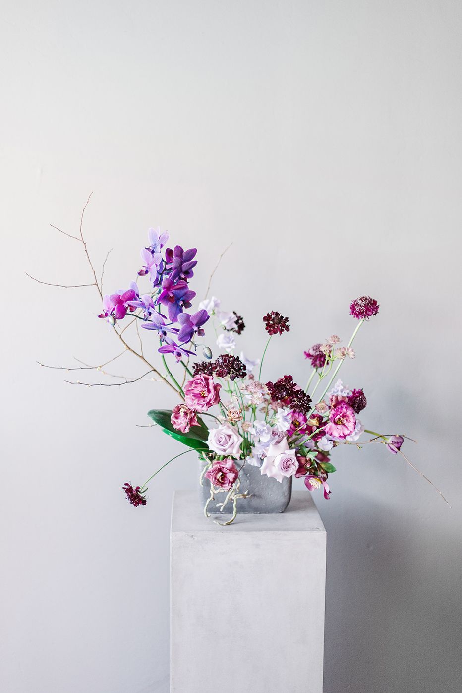 A vase filled with purple and pink flowers is sitting on a pedestal.