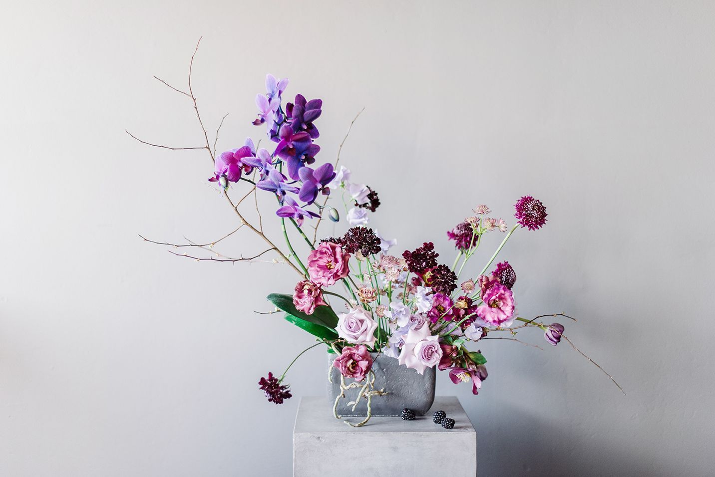 A vase filled with purple and pink flowers is sitting on a concrete block.