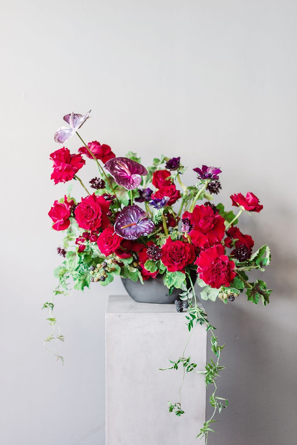 A vase filled with red flowers is sitting on a pedestal.