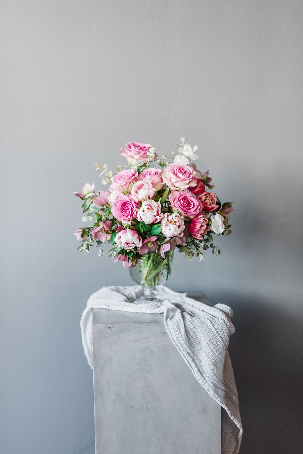 A bouquet of pink and white flowers in a vase on a pedestal.