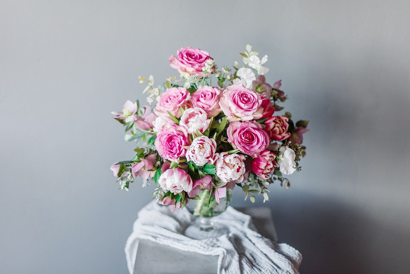 A vase filled with pink and white flowers is sitting on a table.