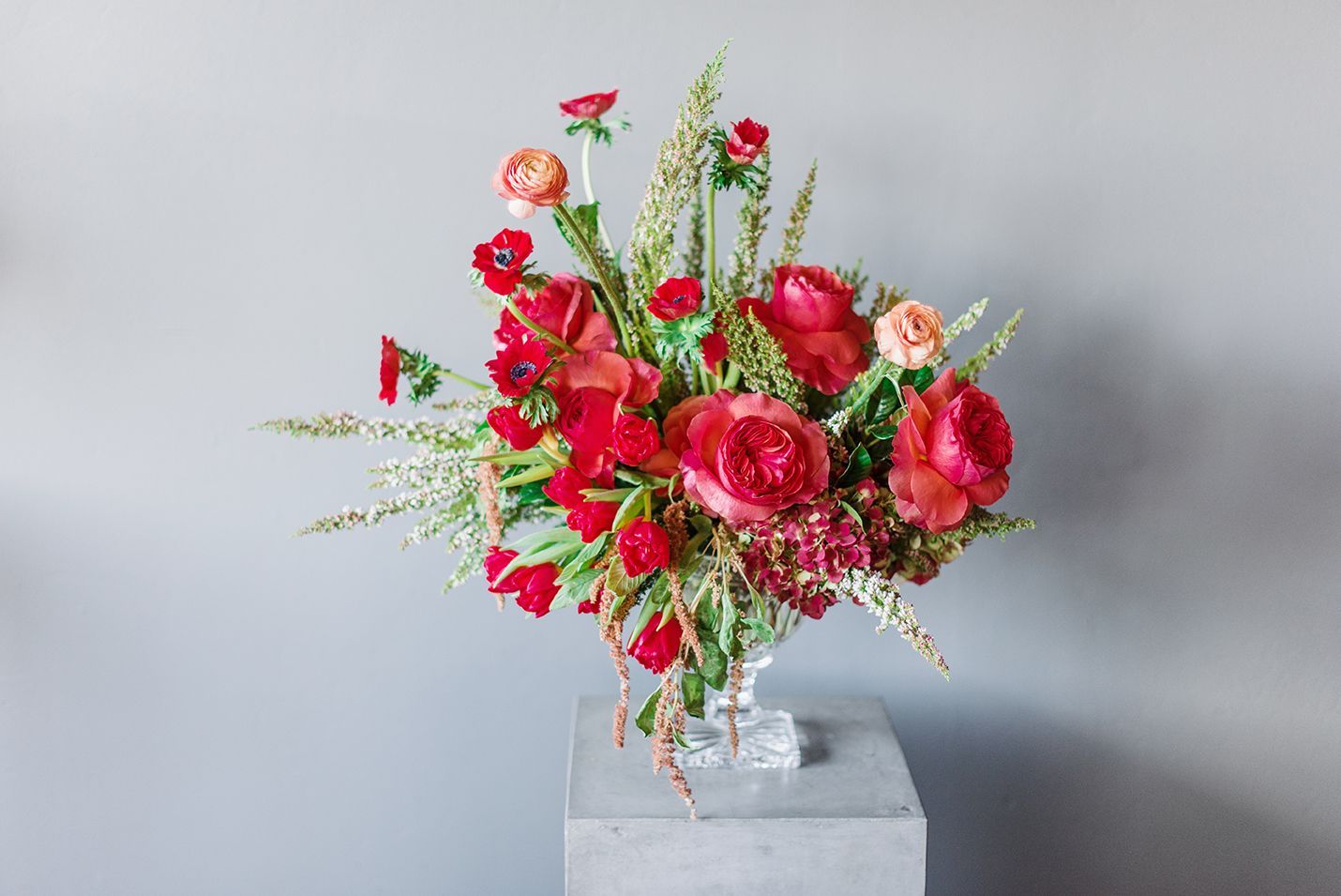 A vase filled with red flowers is sitting on a table.