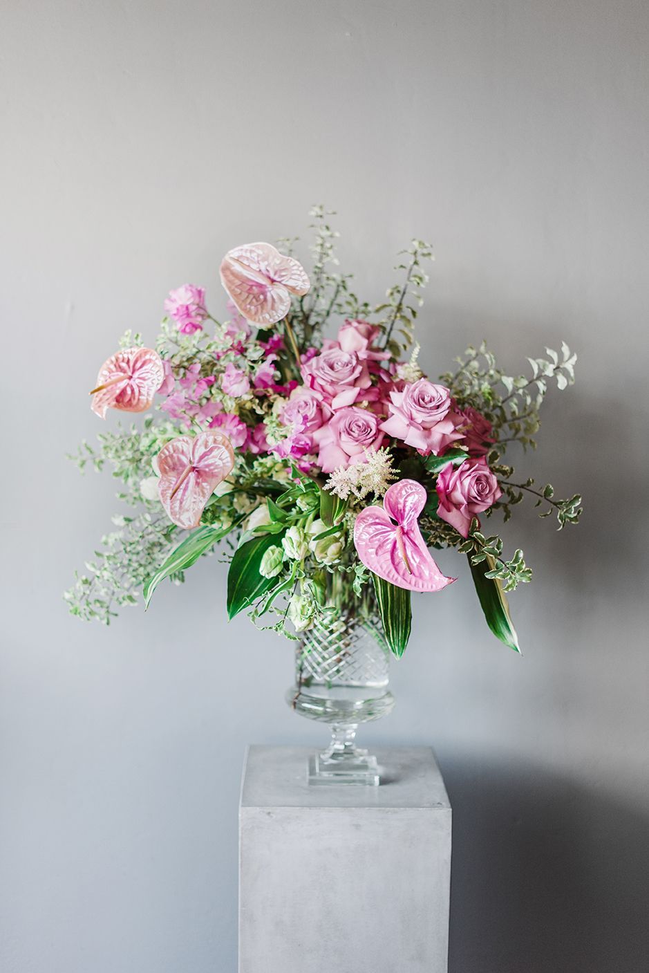 A vase filled with pink flowers is sitting on top of a concrete pedestal.
