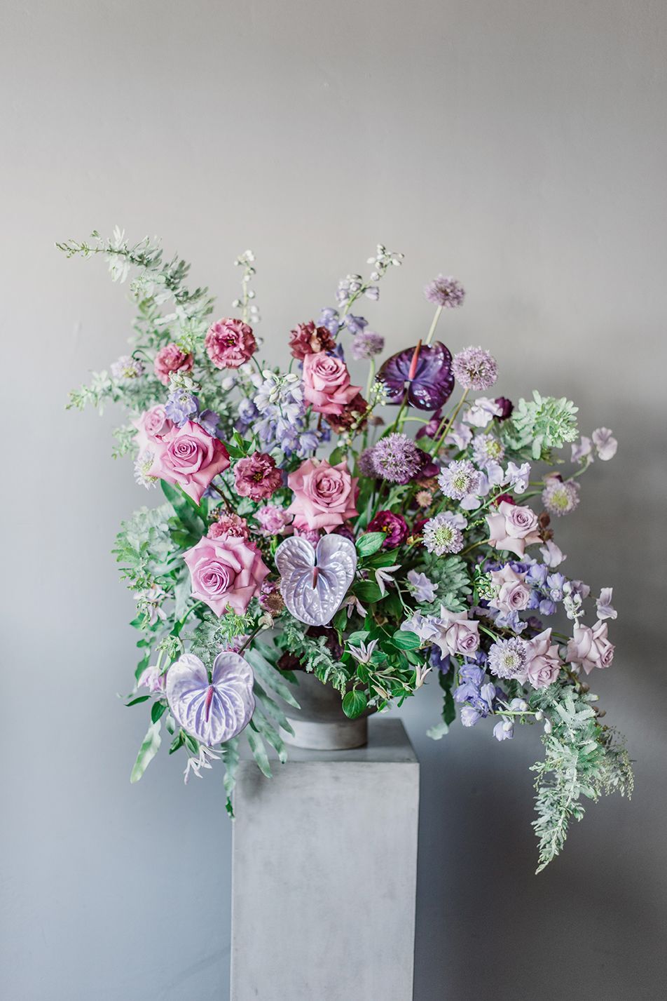 A vase filled with purple and pink flowers is sitting on a pedestal.