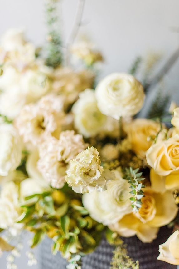 A close up of a vase filled with yellow and white flowers.