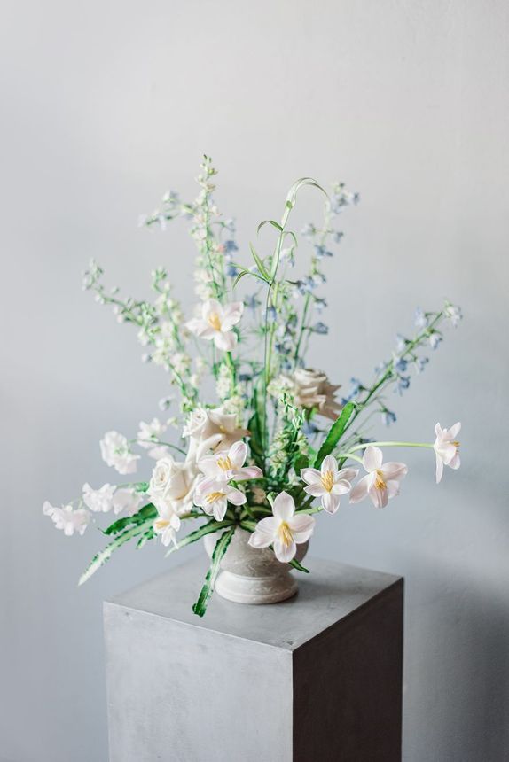 A vase filled with white flowers is sitting on top of a concrete block.