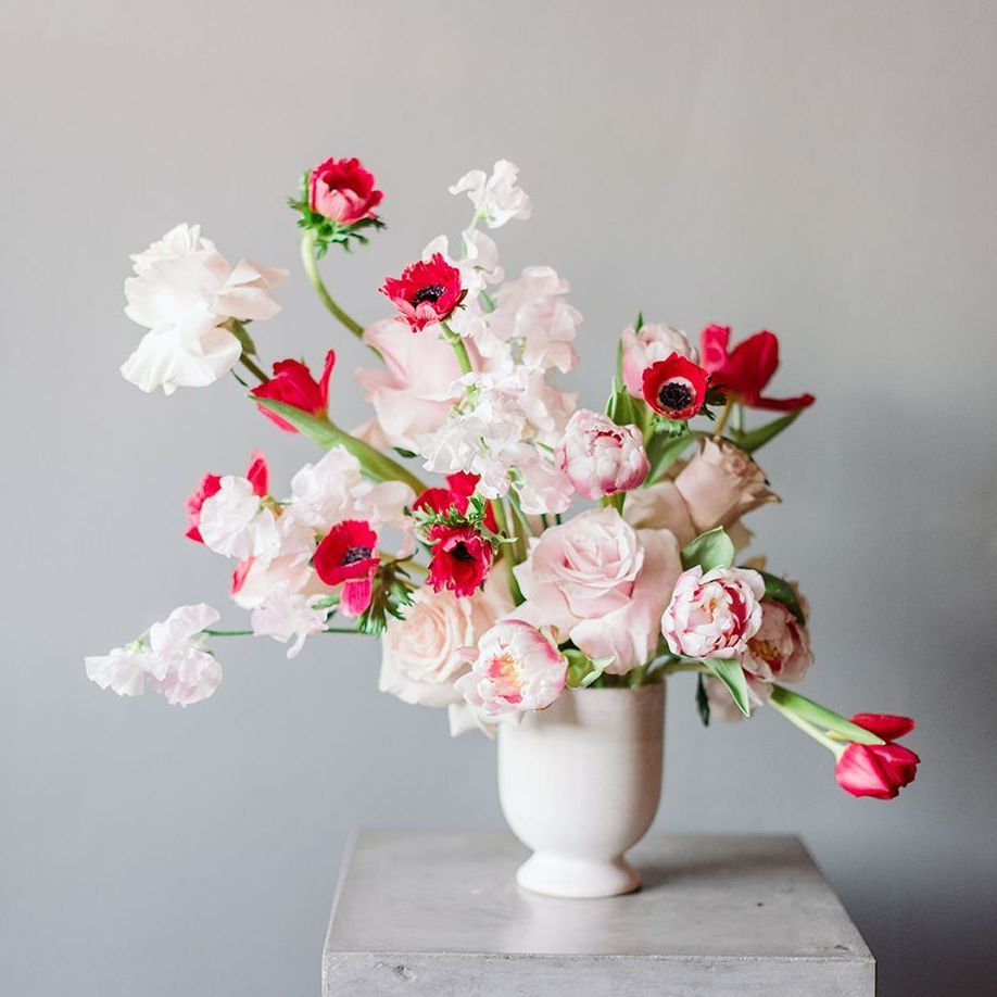 A white vase filled with pink and red flowers