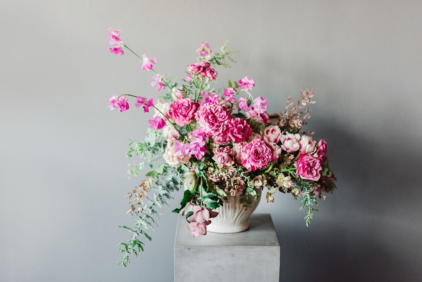 A vase filled with pink flowers is sitting on top of a concrete block.