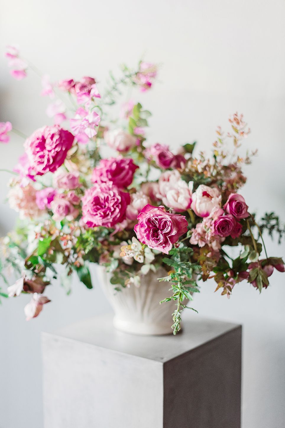 A vase filled with pink flowers is sitting on top of a concrete block.