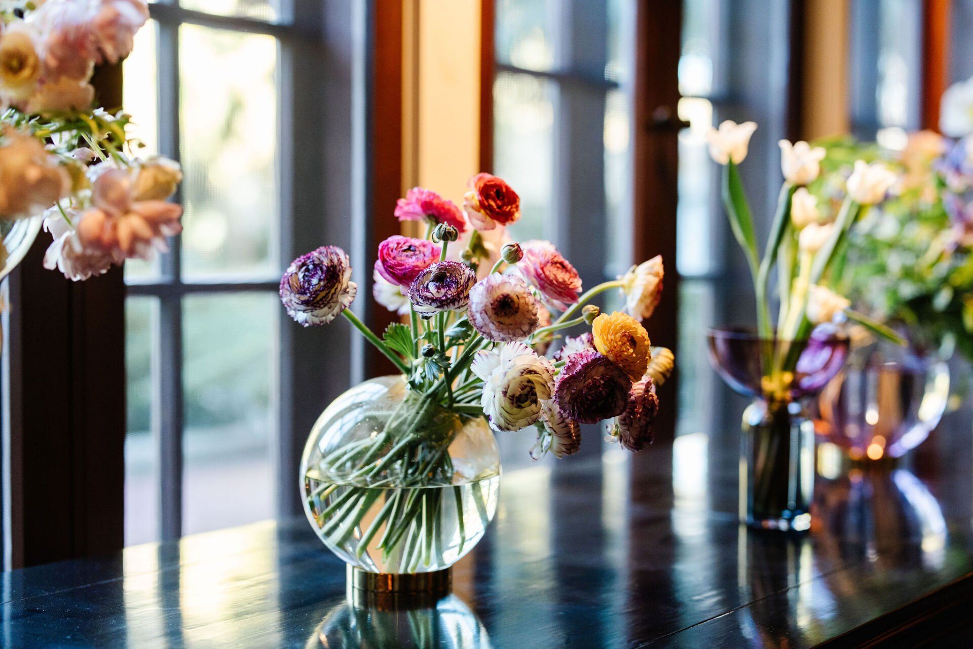 A vase filled with flowers is sitting on a table in front of a window.
