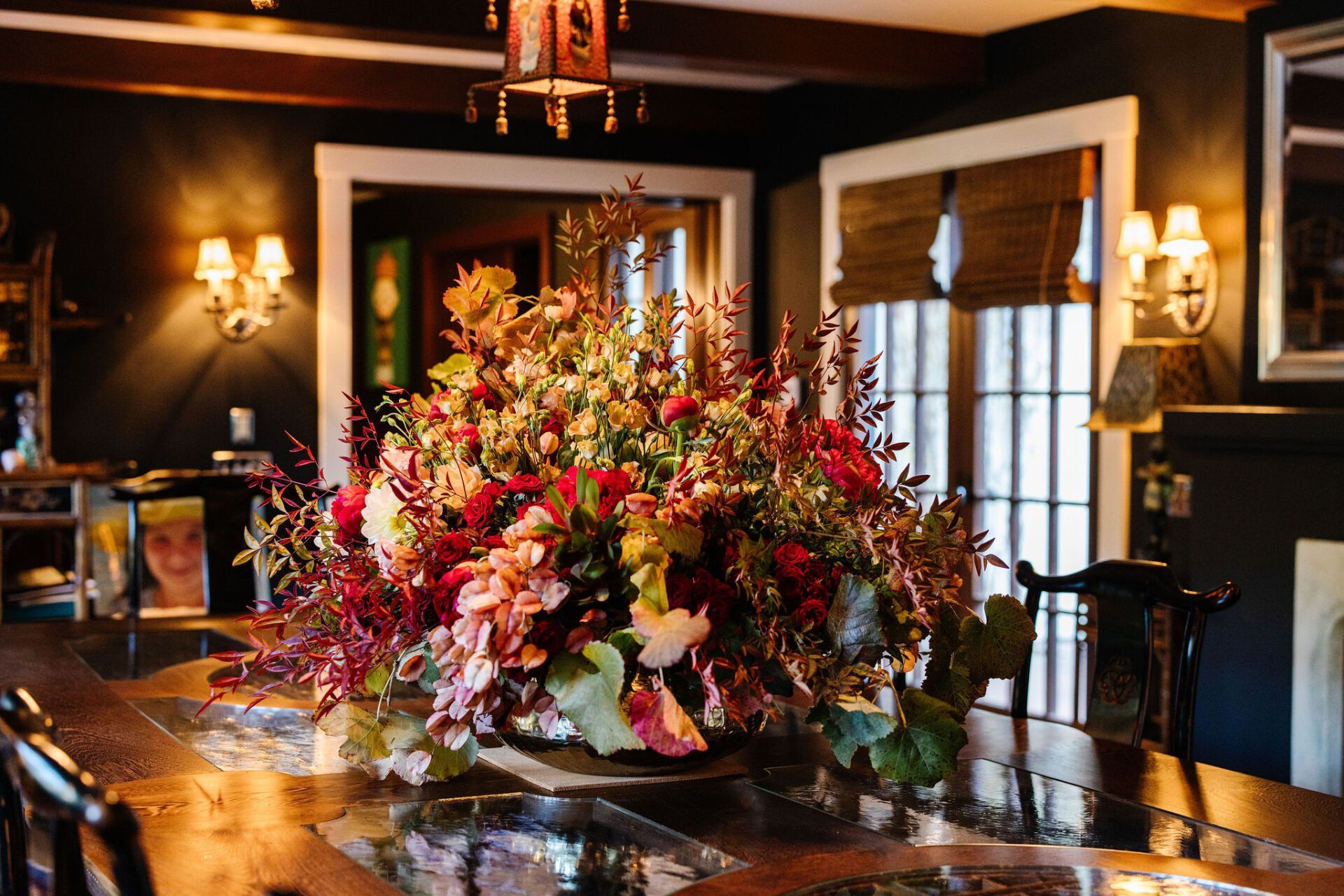 A large vase of flowers is on a table in a dining room.