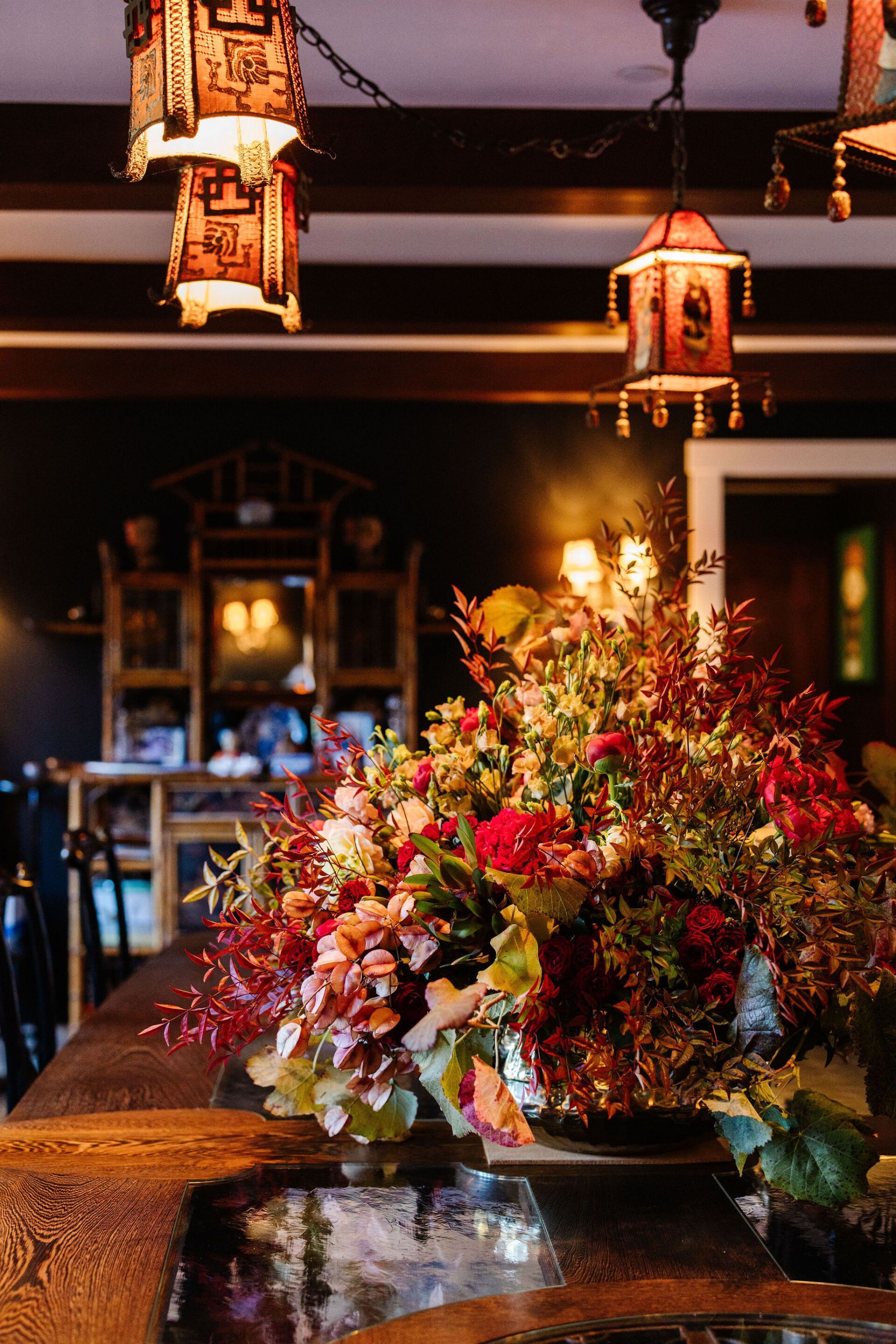 A vase of flowers is sitting on a table in a room with lanterns hanging from the ceiling.