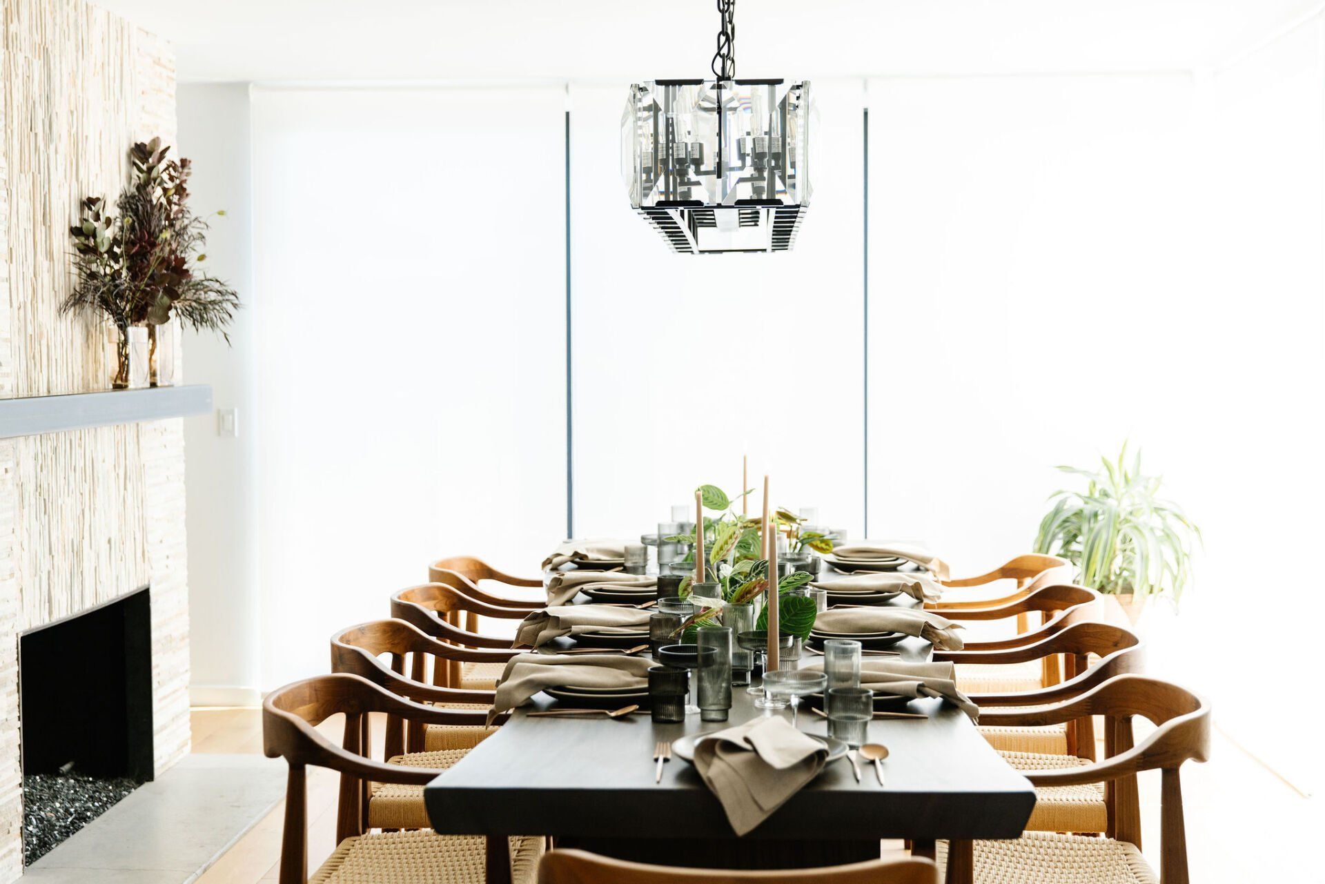 A dining room with a long table and chairs and a fireplace.