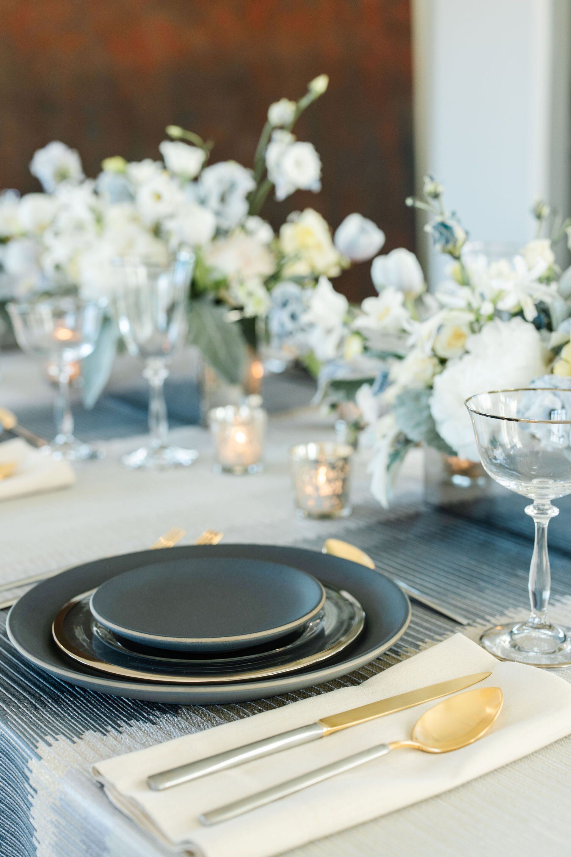 A table setting with plates , silverware , and a vase of flowers.