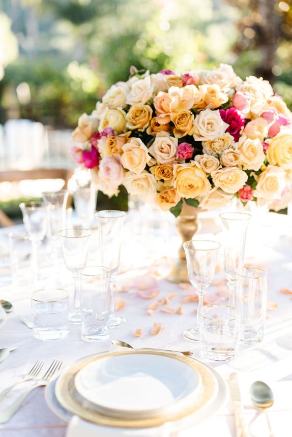 A table with plates , glasses , and a vase of flowers on it.