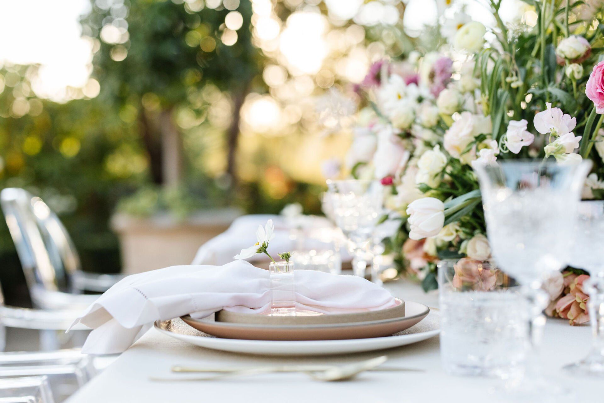 A table set for a wedding reception with plates , silverware , glasses and flowers.