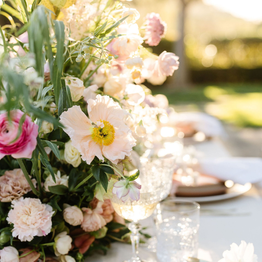 A table with plates , glasses , and flowers on it.