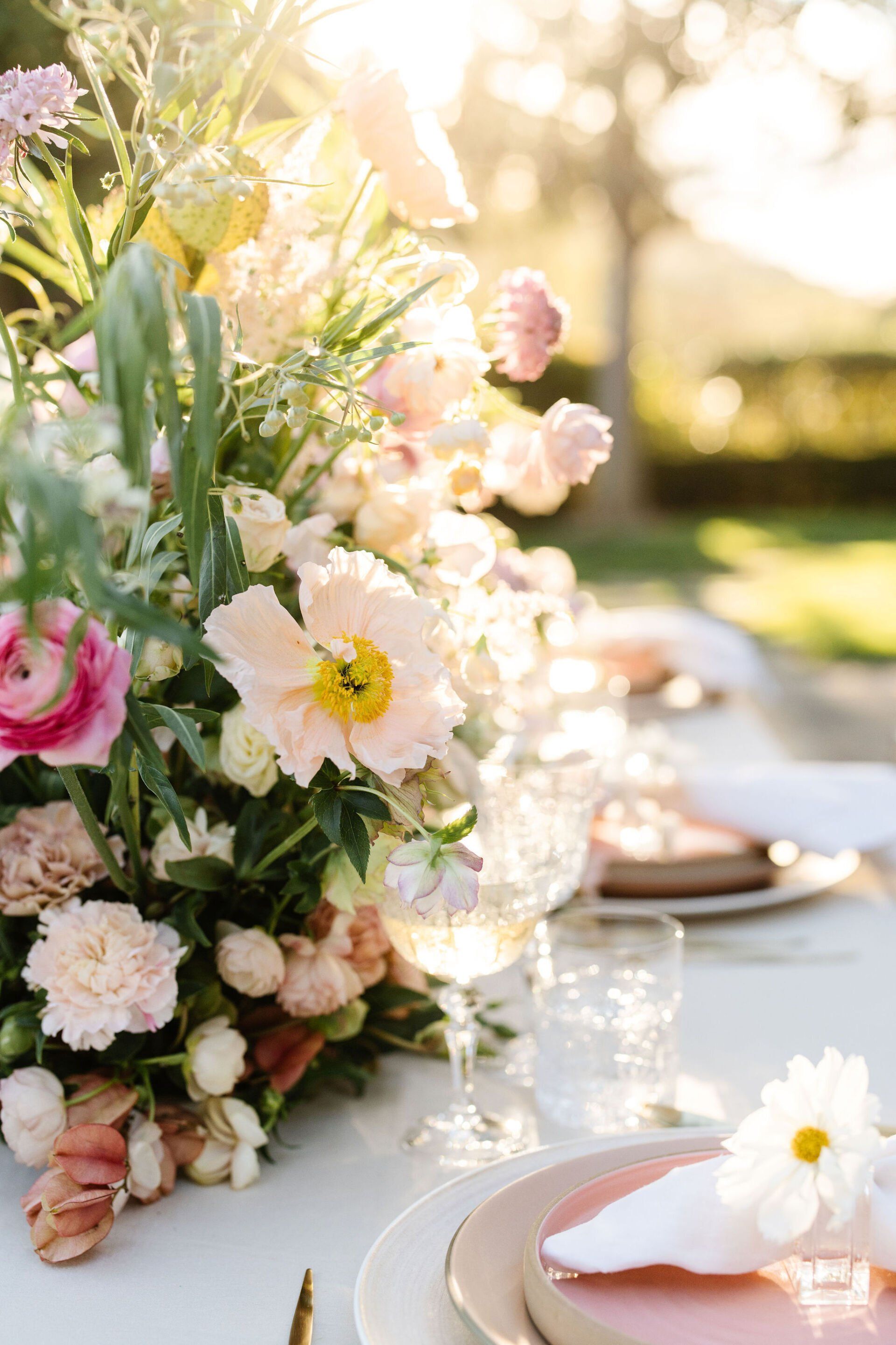 A table with plates , glasses , and flowers on it.