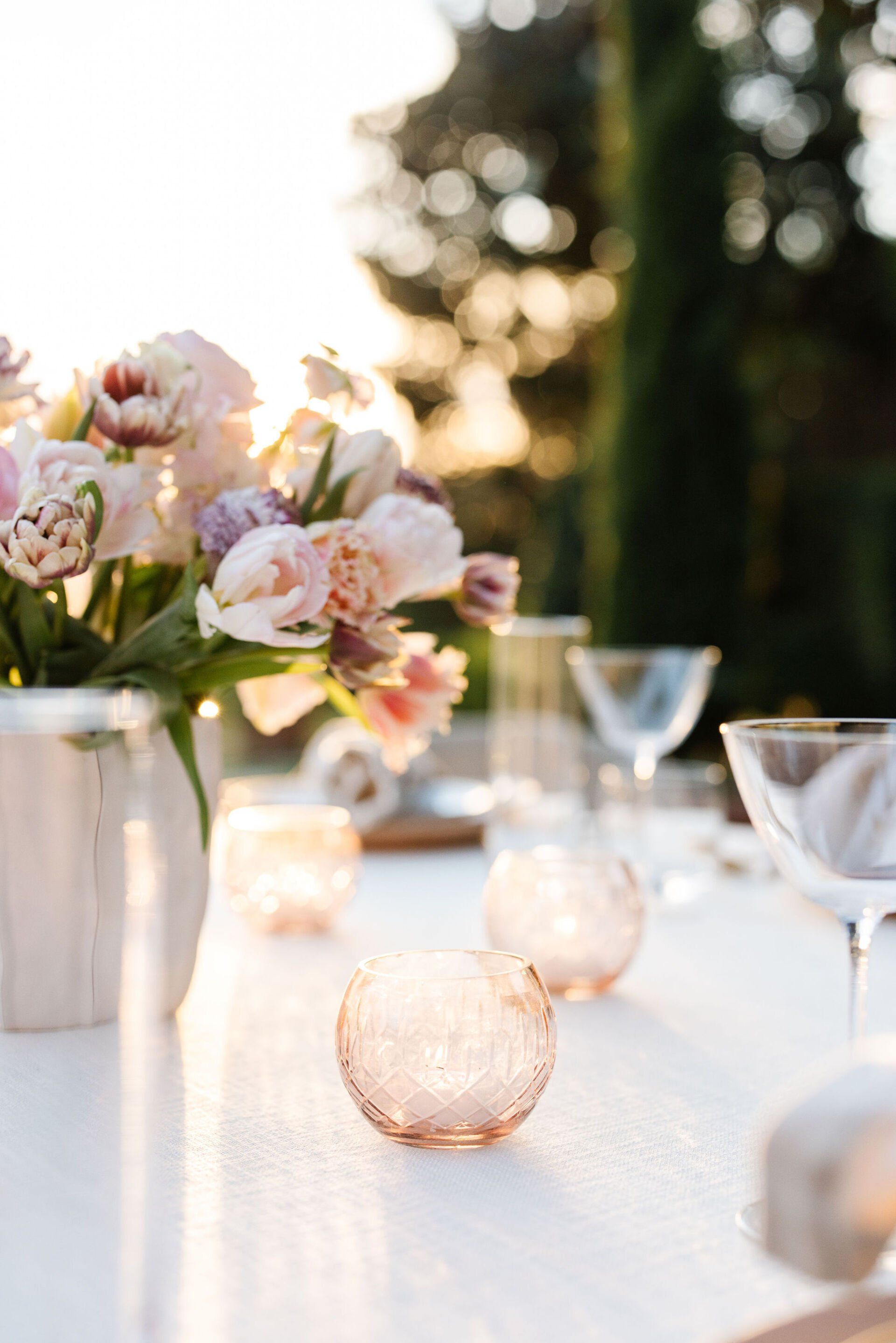 A table with a vase of flowers and candles on it.