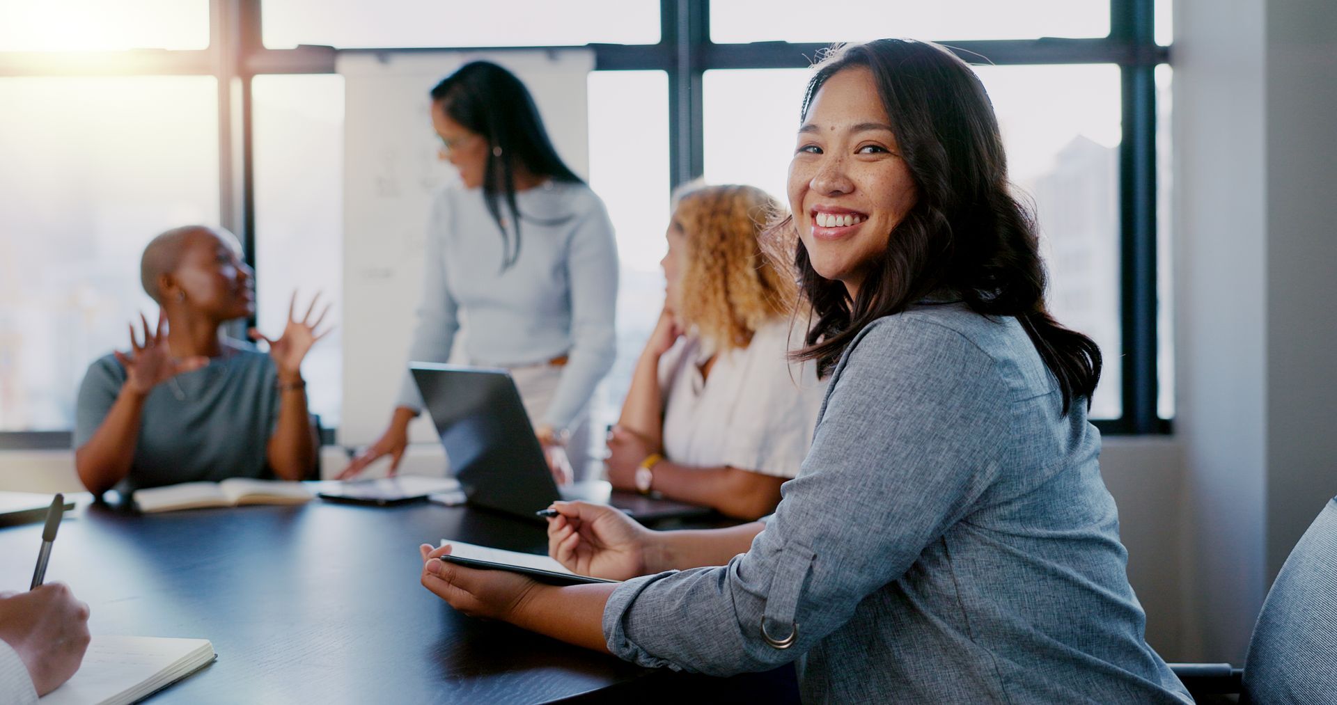 A woman is sitting at a table with a group of people in a conference room.